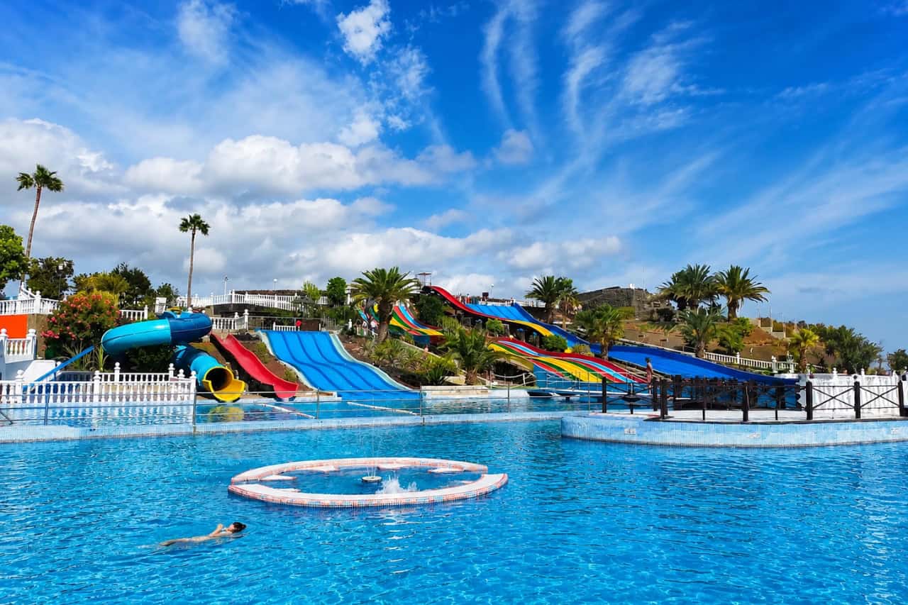 Main swimming pool at Aquapark Costa Teguise with colorful water slides, palm trees and family areas at this popular Lanzarote waterpark.