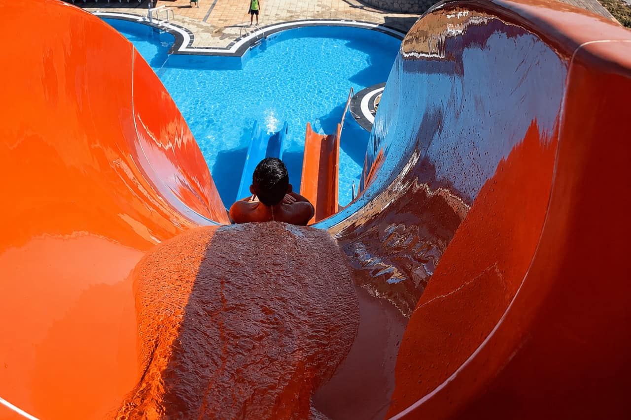 Visitors enjoying a fast ride down an orange water slide at a Fuerteventura water park.