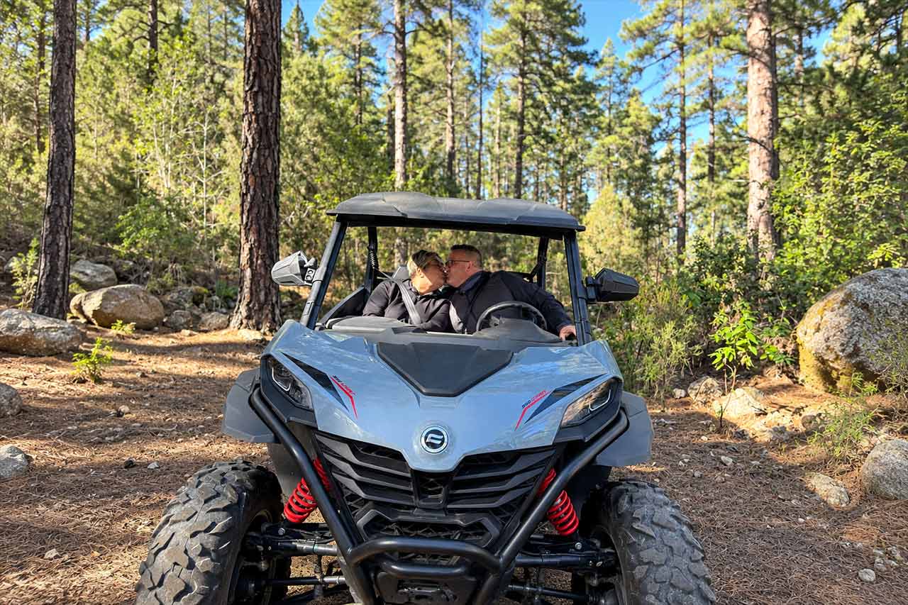 A couple enjoys a relaxed stop beside their buggy in the forested countryside of North Tenerife, showing the fun and personal side of the Puerto de la Cruz buggy experience.