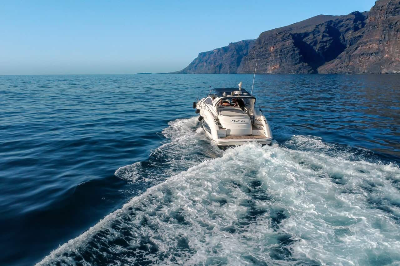 A private Club Canary yacht charter cruising past the iconic Los Gigantes cliffs in Tenerife, an example of the premium experiences we curate across the Canary Islands