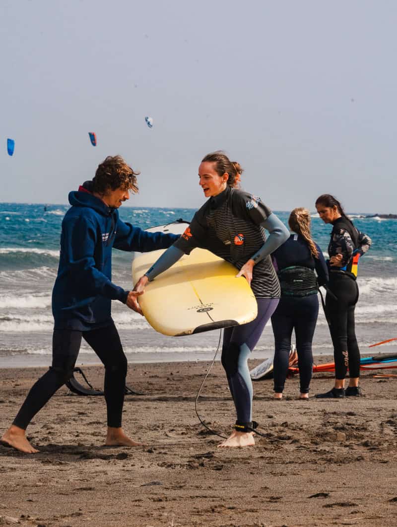 Water sports El Médano - surf instructor helping stoked student with longboard at Playa Sur Tenerife booked with Club Canary