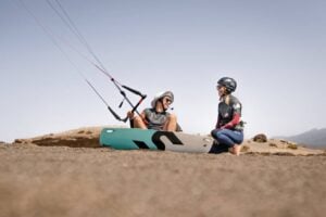 Beginner kitesurf lesson Tenerife - instructor teaching student kite bar control on El Médano sand booked with Club Canary