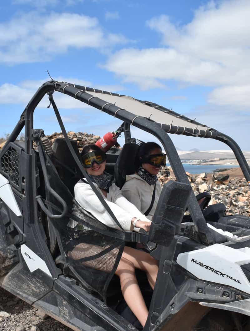 Dvi besišypsančios merginos su akiniakiais "Can-Am" bagi sulėkdamos šeimos safarietį Fuerteventūroje