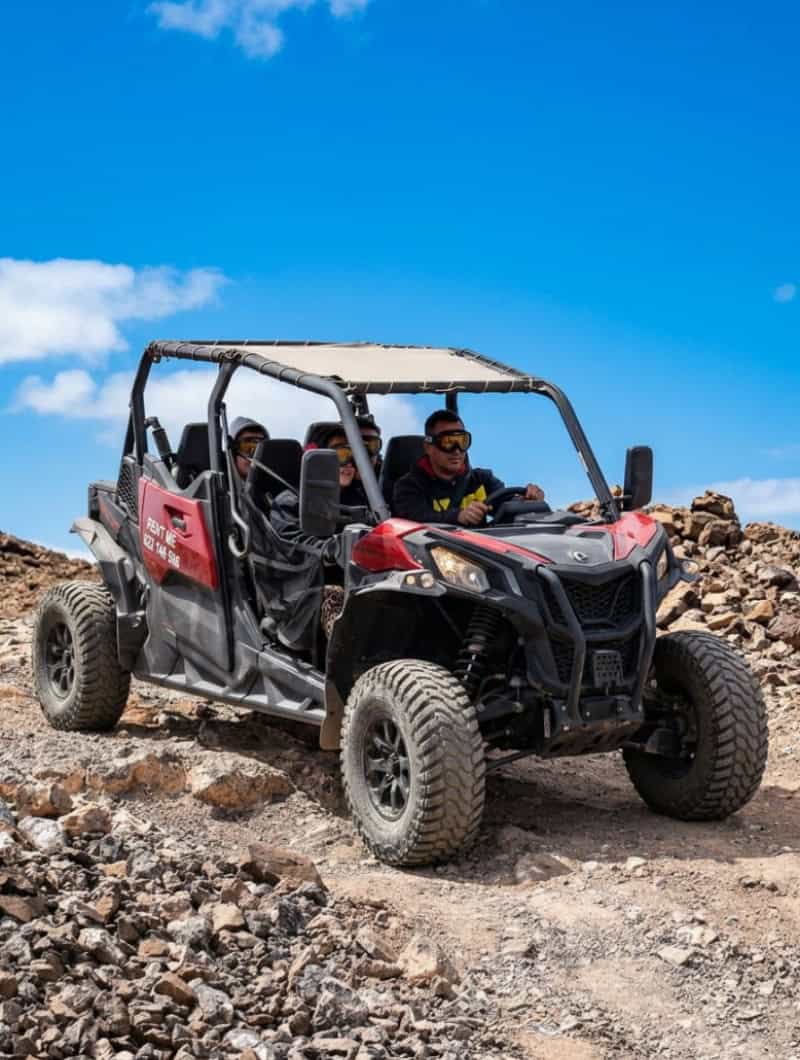 Four people wearing goggles riding a red Can-Am buggy off-road in Fuerteventura