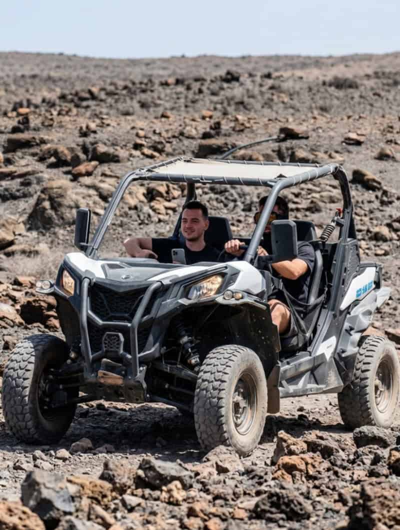 Two friends driving a Can-Am buggy off-road across volcanic landscape in southern Fuerteventura