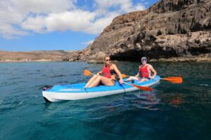 Couple kayaking in clear water below the cliffs near Morro Jable, Fuerteventura