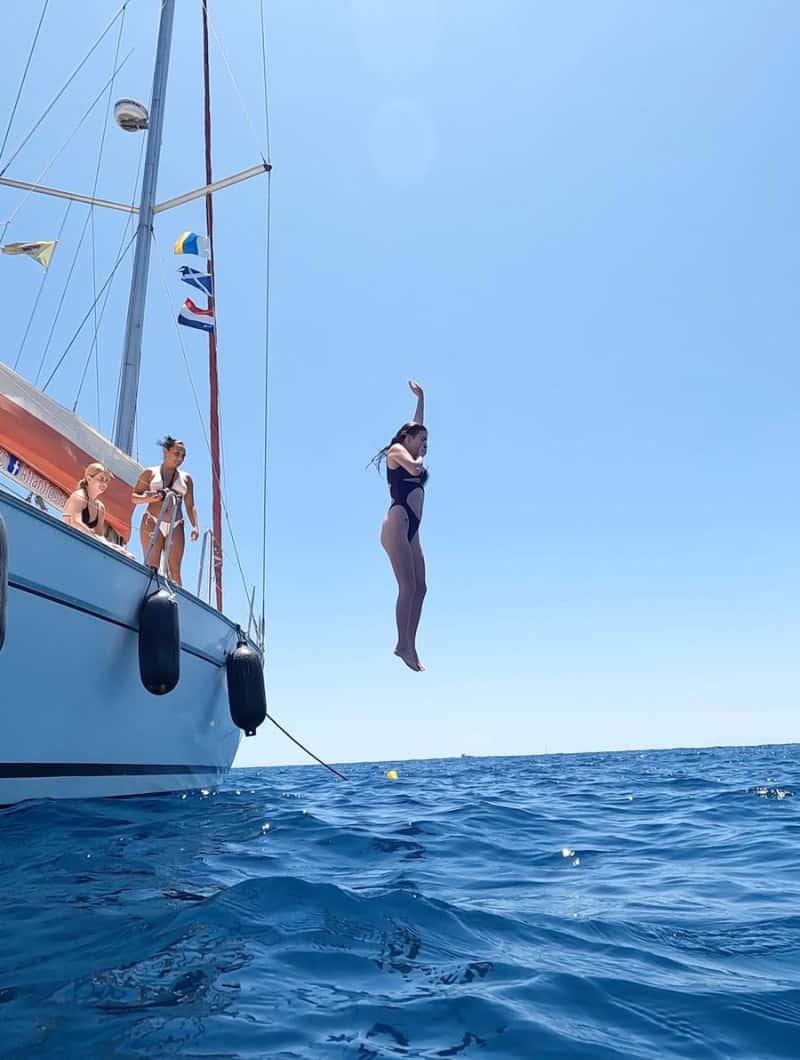 Guest jumping off the sailing boat into the ocean during the swim and snorkel break of a Tenerife whale watching tour