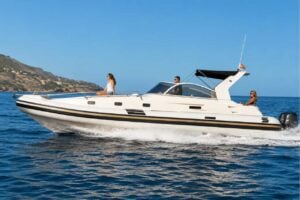 White 11-metre luxury speedboat cruising along the Tenerife coastline with calm blue sea and volcanic cliffs in the background, available for private boat hire.