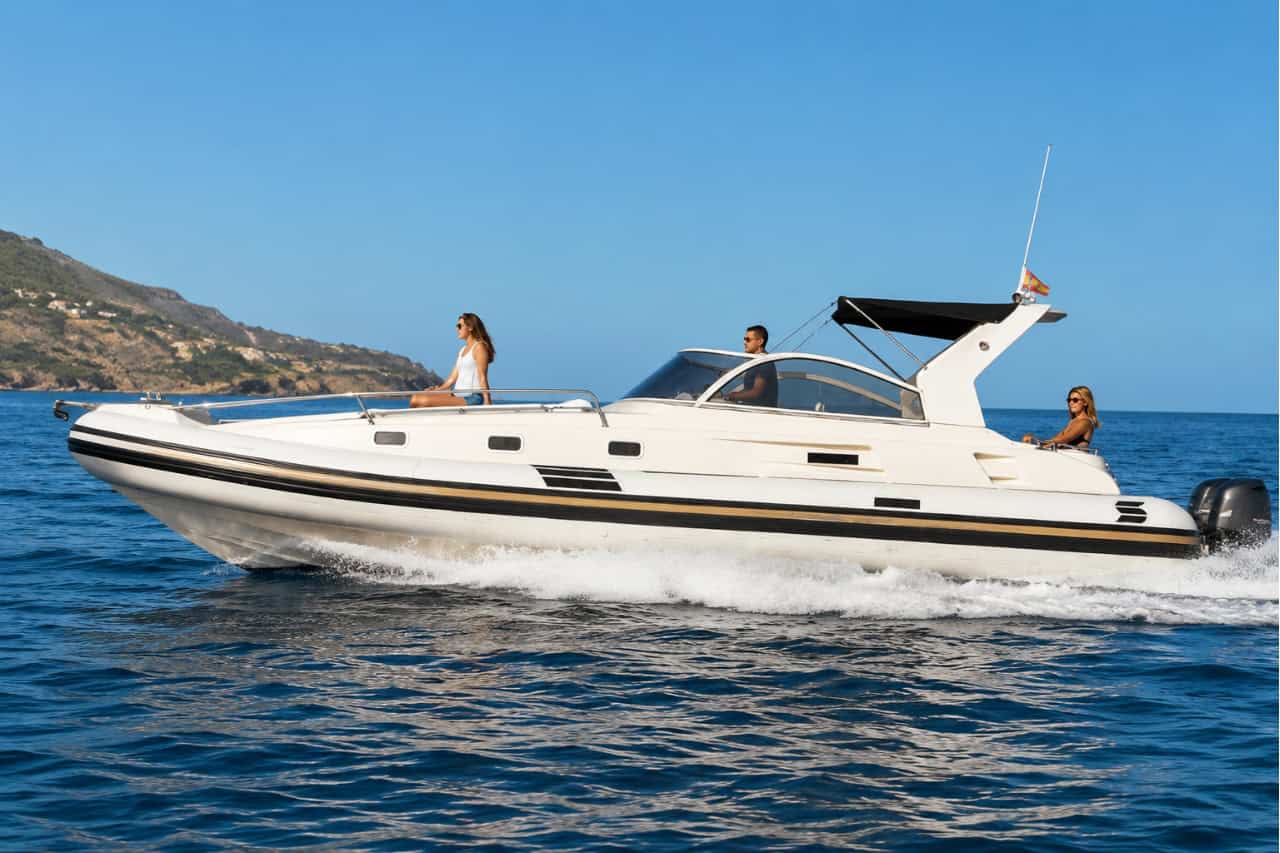 White 11-metre luxury speedboat cruising along the Tenerife coastline with calm blue sea and volcanic cliffs in the background, available for private boat hire.