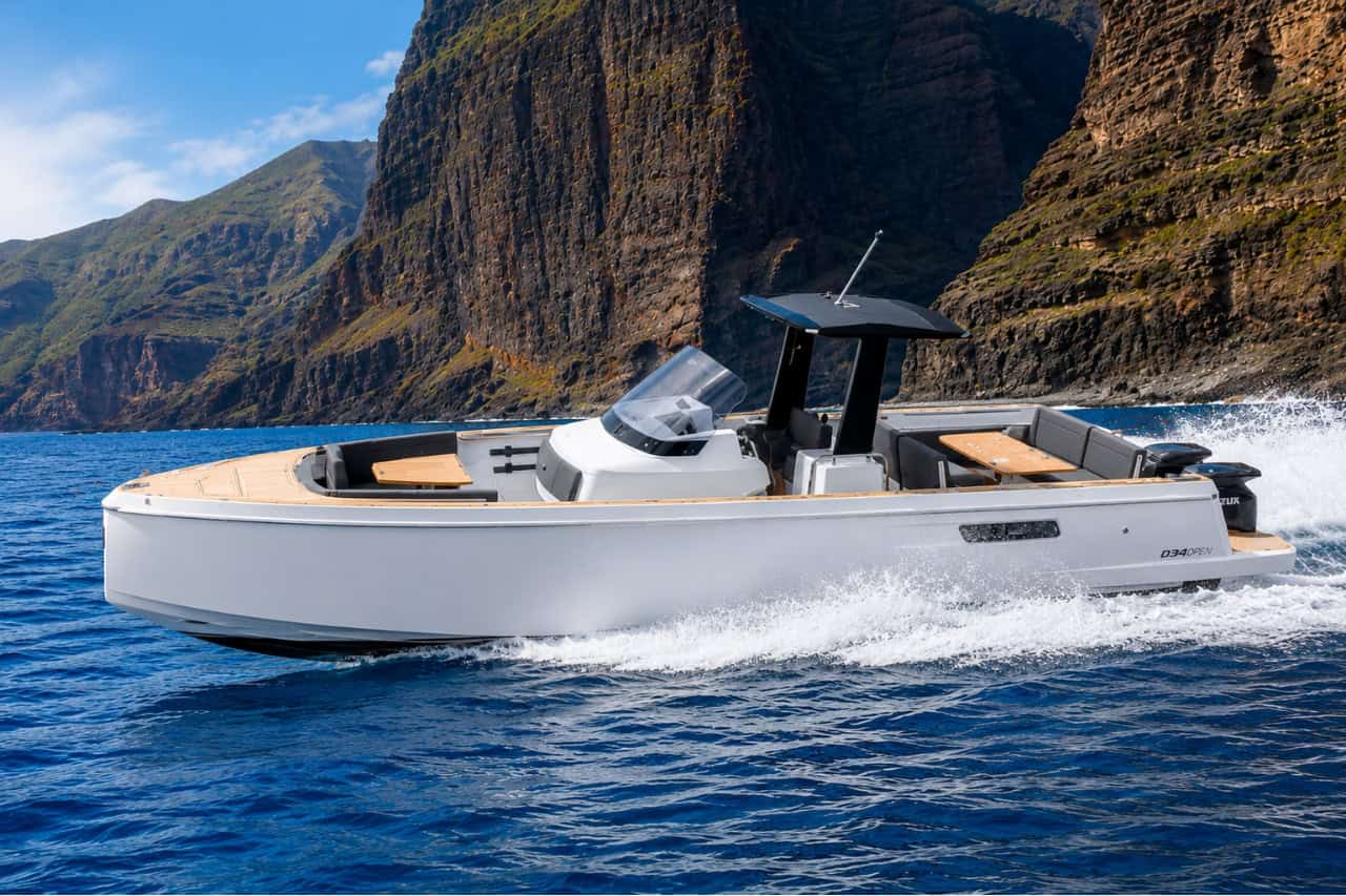 Modern 11-metre white luxury motor boat cruising along the dramatic cliffs of Tenerife with no passengers visible, surrounded by clear blue Atlantic waters.
