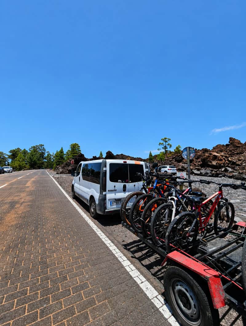 Arriving at the Starting Point for the Mount Teide Bike Tour Minivan and trailer loaded with mountain bikes parked in the volcanic landscape before the group prepares for the downhill bike tour.