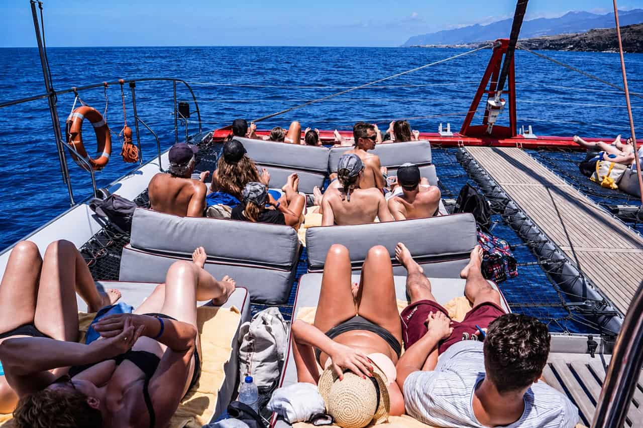 Guests relaxing on the spacious deck of a catamaran while sailing along Tenerife’s sunny coastline.