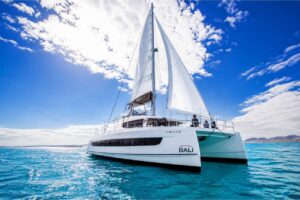Large luxury sailing catamaran cruising on the turquoise waters off Corralejo, Fuerteventura during a private party boat charter with guests on board.