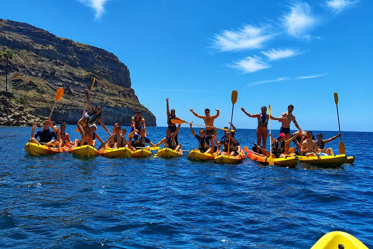 Group of people kayaking along coastline of Gran Canaria during a guided sea kayak tour on a sunny day