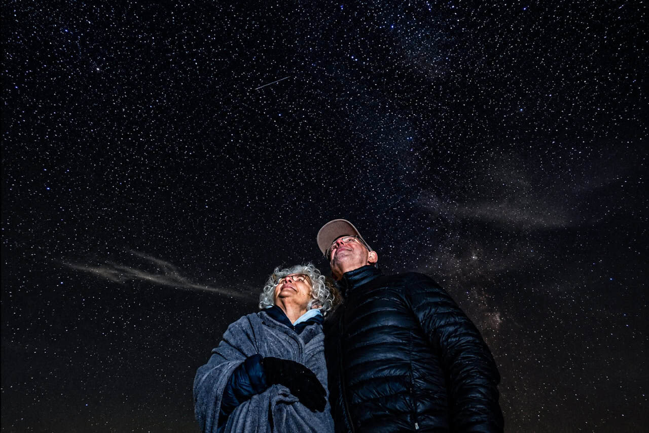 Mature couple looking up at the stars during a guided stargazing experience in Gran Canaria beneath a clear, star-filled night sky.