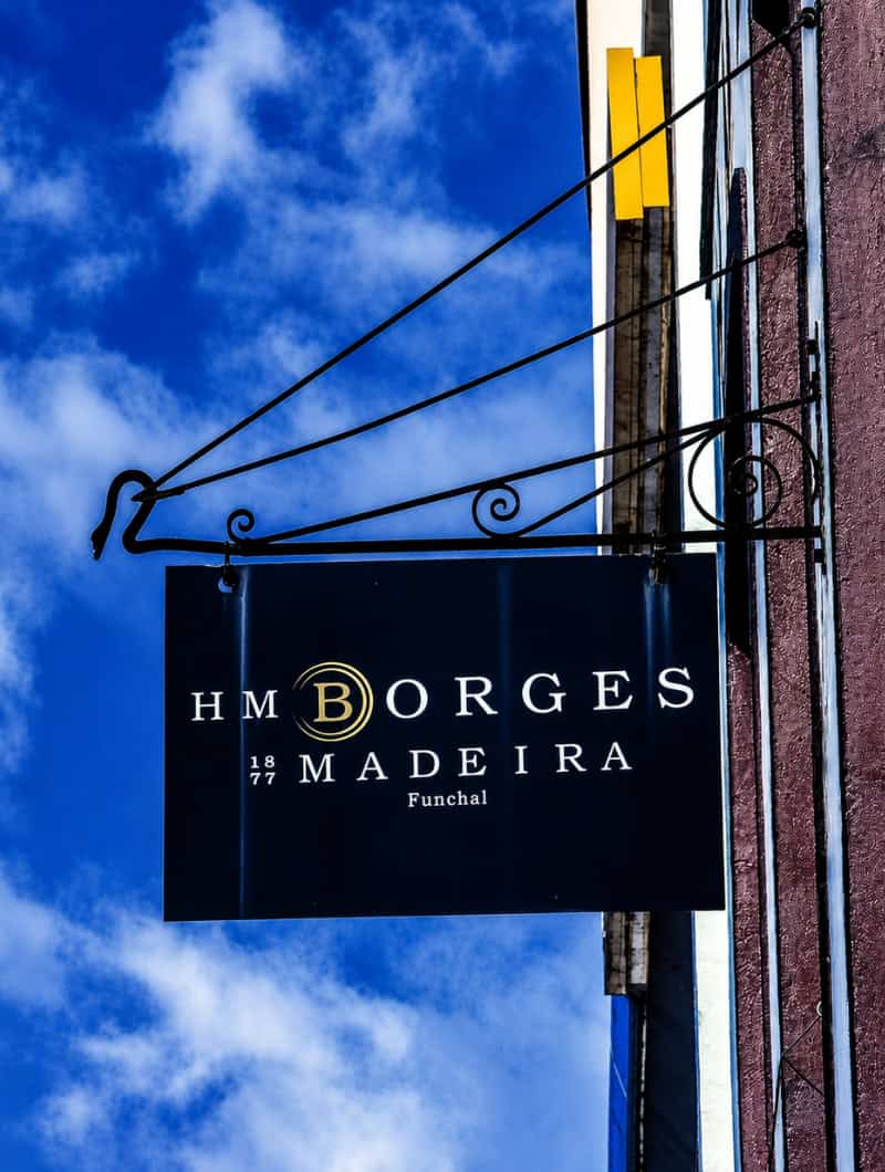Sign of the H.M. Borges Madeira wine lodge against a blue sky in Funchal