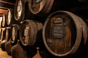 Rows of traditional wooden Madeira wine barrels aging inside the historic H.M. Borges wine lodge in Funchal.