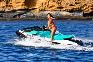 Woman riding a Sea-Doo jet ski along the Tenerife coast during a one-hour jet ski rental experience.