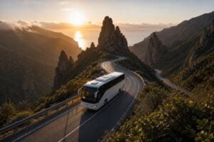 Tour bus driving through the dramatic mountain landscape of La Gomera at sunset, with winding roads, volcanic rock formations and ocean views during a day trip from Tenerife.