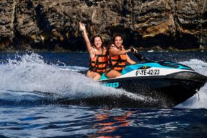 Two women riding a jet ski near the Los Gigantes cliffs during a Tenerife jet ski safari.