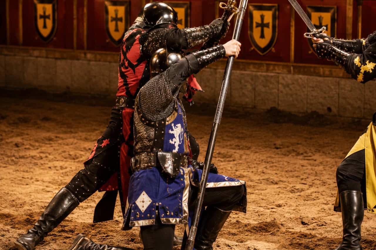 Armored knights battling with swords and polearms during a live combat performance at the Medieval Adventure Dinner Show in Tenerife.