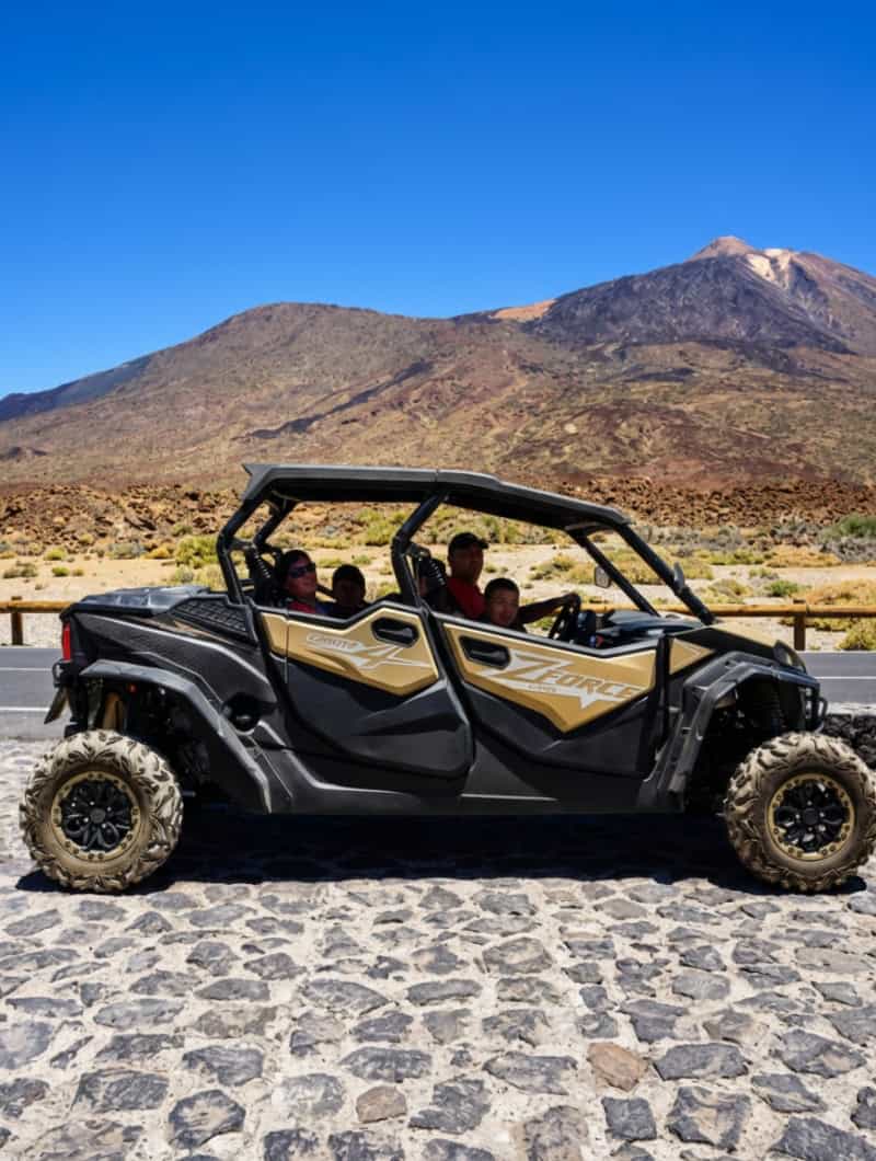 Family sitting in a 4-seat Monster Buggy during a guided Teide buggy tour in Tenerife with volcanic mountain scenery in the background.