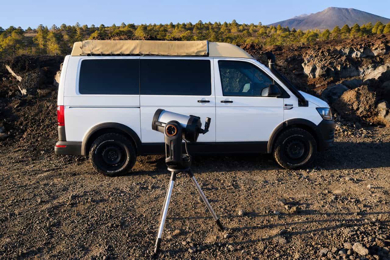 White stargazing tour van and telescope set up on volcanic terrain near Mount Teide in Tenerife.