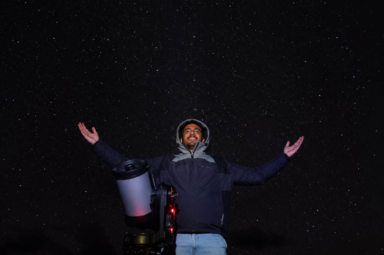 Guest standing beside a telescope under a star-filled sky during the Mount Teide Stargazing Experience in Tenerife.