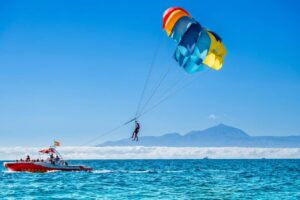 Parasailing in Gran Canaria from Puerto Rico, a rider flying under a parachute behind the boat.