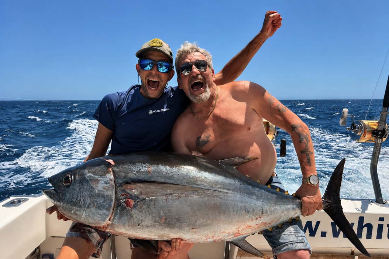 Two anglers celebrating with a giant tuna aboard a private fishing charter boat in Gran Canaria.