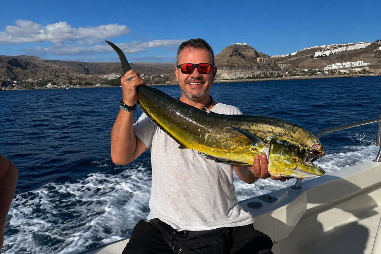 Angler holding a freshly caught mahi-mahi during a private fishing charter along the Gran Canaria coastline.