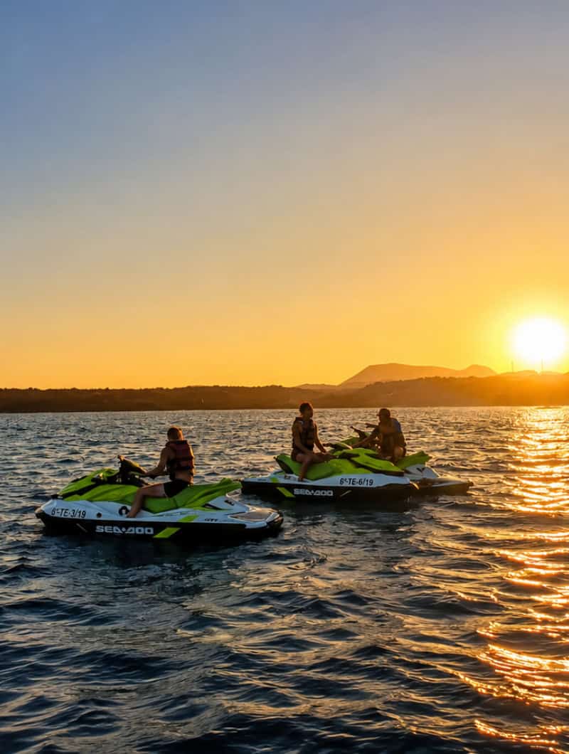 Private jet skis stopped together on a calm sea during a golden sunset private jet ski trip in Tenerife.