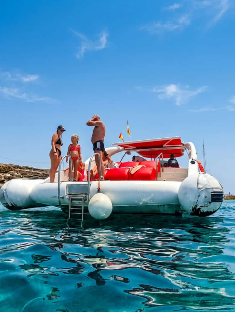 Guests relaxing on the red cushions of the Opera 60 private boat during a swim stop off the coast of Tenerife