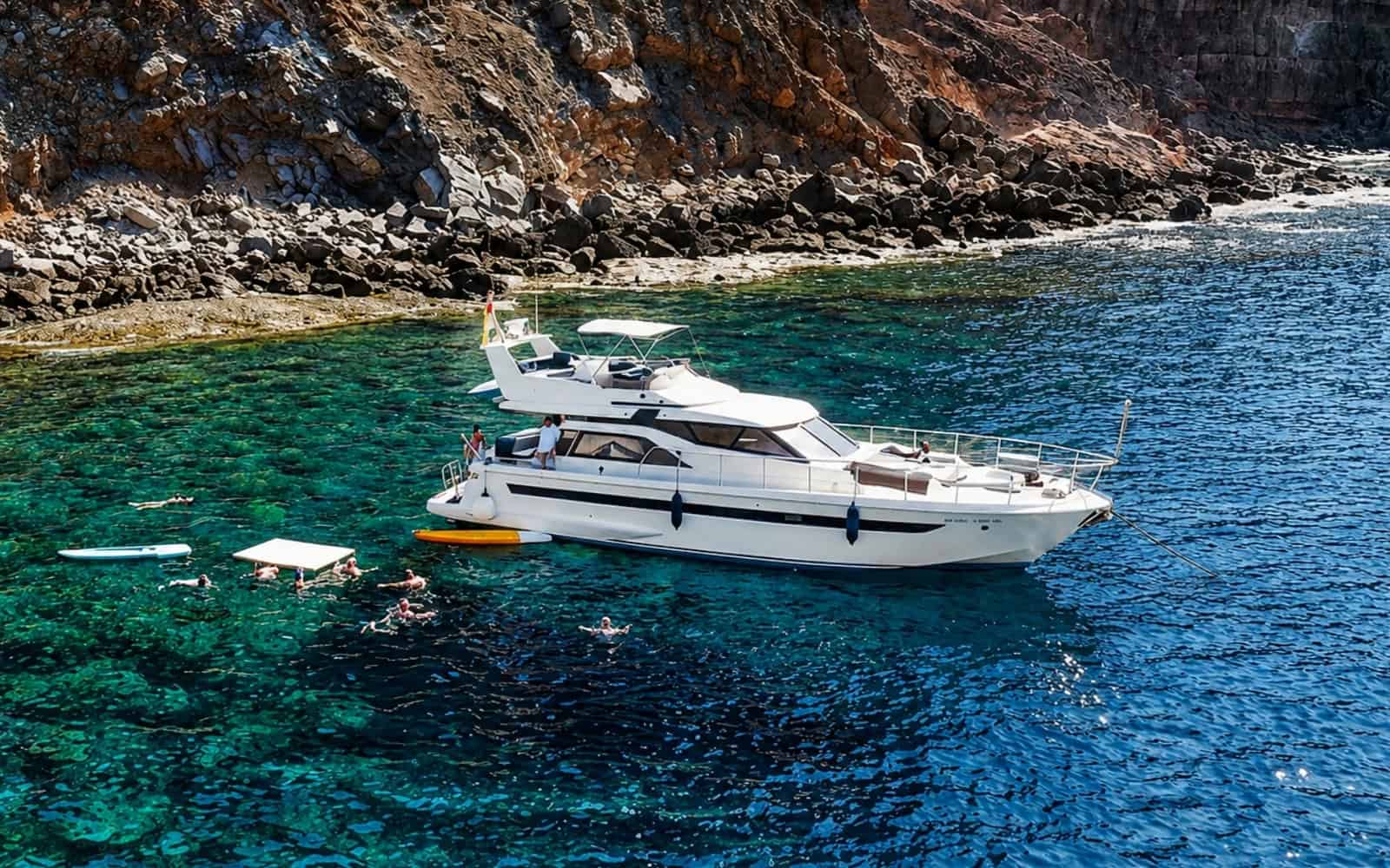 Guests swimming beside a private yacht near the coast of Gran Canaria