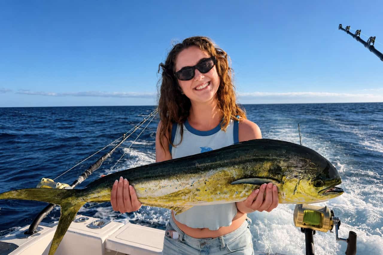 Smiling woman holding a mahi-mahi during a private fishing charter off the south coast of Gran Canaria.