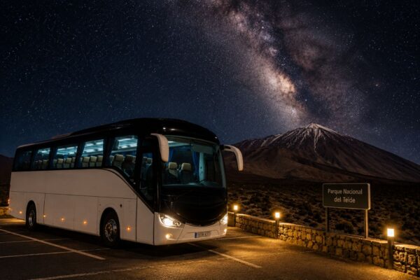 White tour bus parked in Teide National Park at night beneath the Milky Way, with Mount Teide and the star-filled sky in the background.