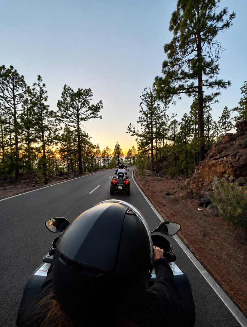 Rider following another quad through Tenerife pine forest roads during the sunset return from a Monster Quad Teide tour.