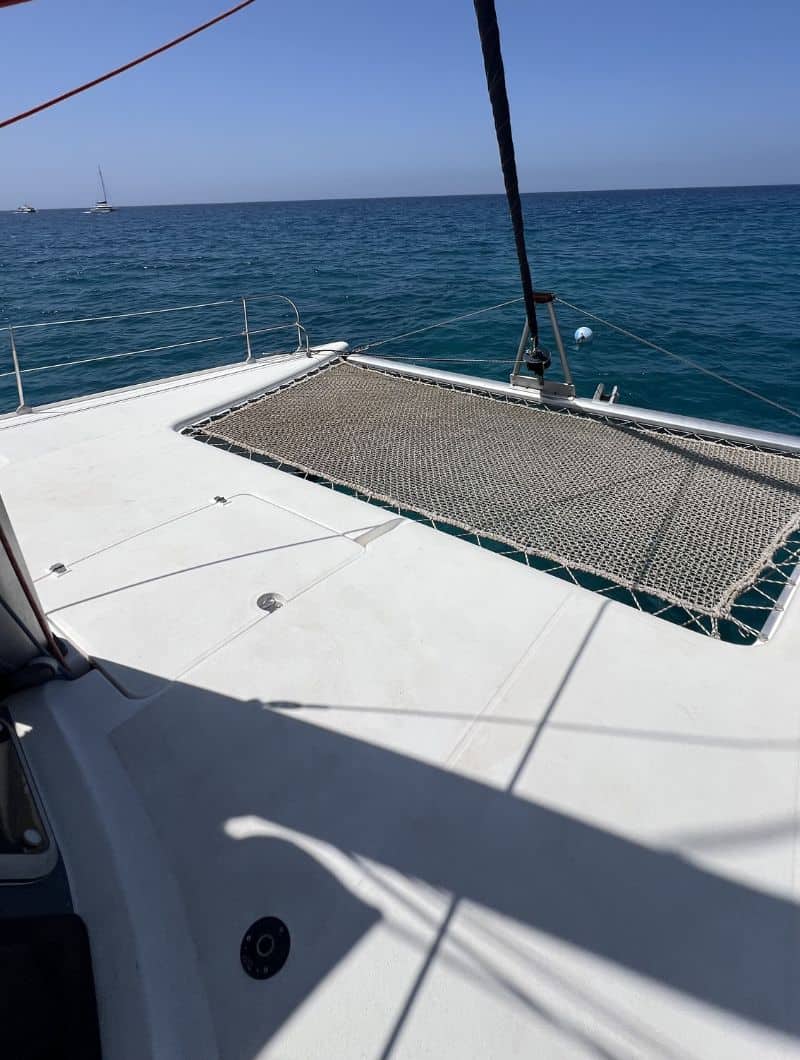 Guest relaxing on the bow net of the small group catamaran from Morro Jable, Fuerteventura