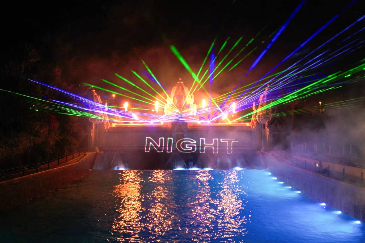Green and blue lasers with the word NIGHT projected over the water at Siam Park Night in Tenerife
