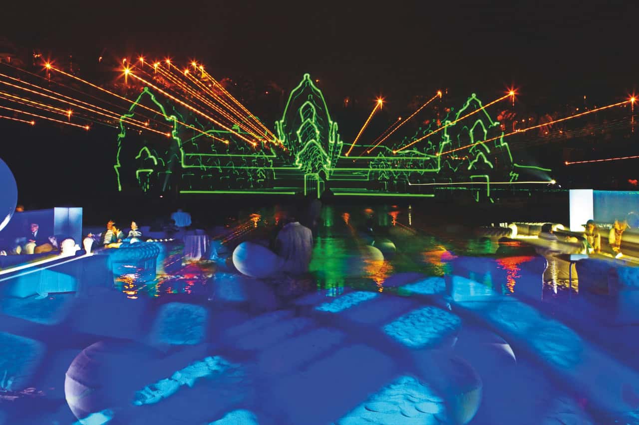 Green laser temple projection and orange lights over the wave pool during Siam Park Night in Tenerife