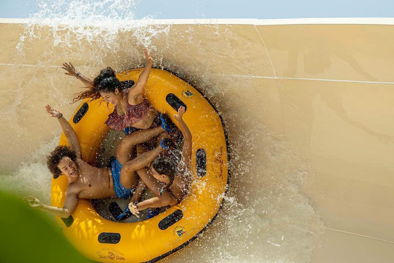 Family splashing down Patong Rapids on a yellow raft at Siam Park, Tenerife