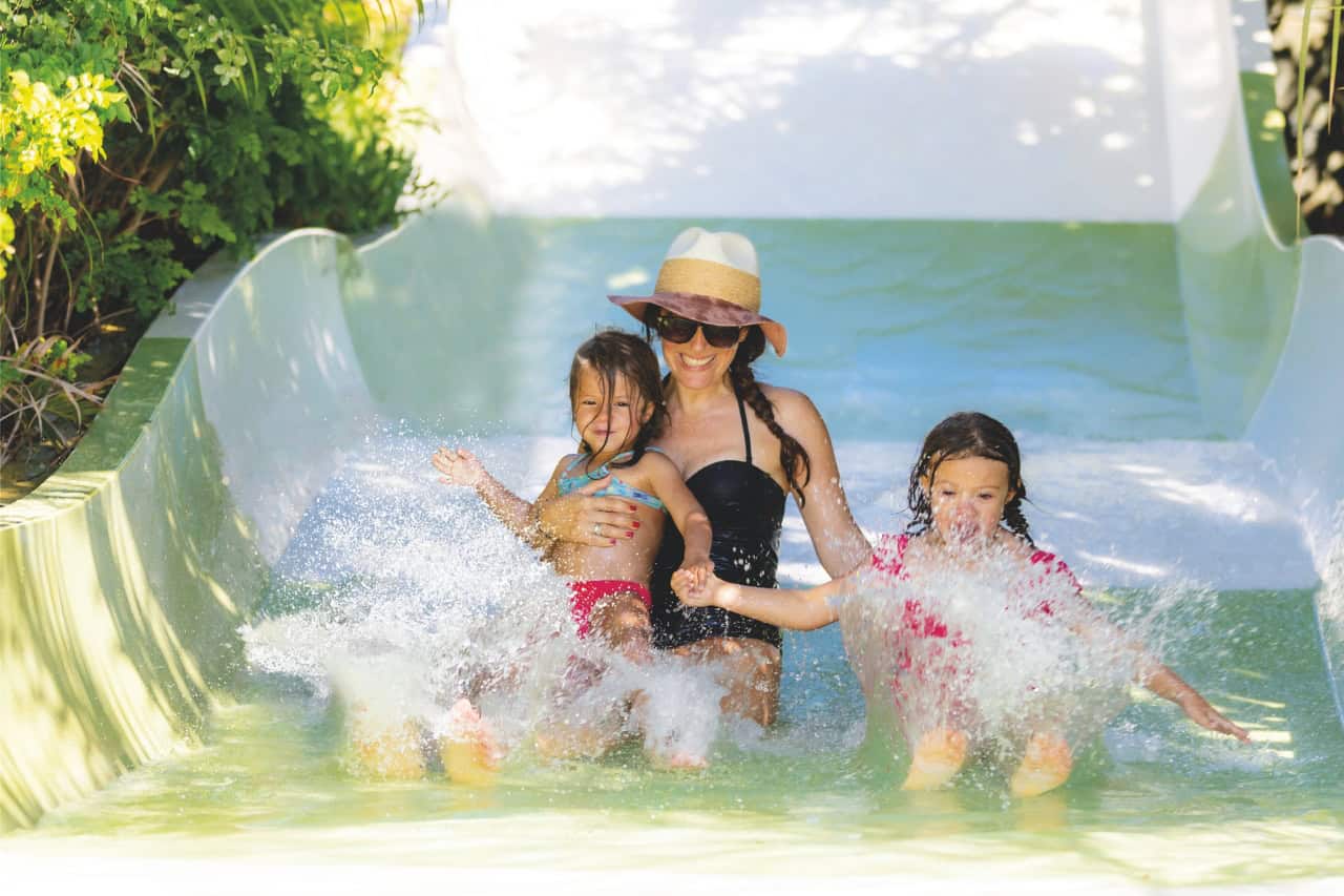A mother and two children splashing down the Sawasdee kids slide at Siam Park, Tenerife