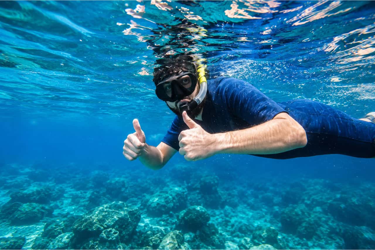 Snorkeler exploring the clear waters off La Lajita, Fuerteventura, giving two thumbs up during a guided snorkeling tour.