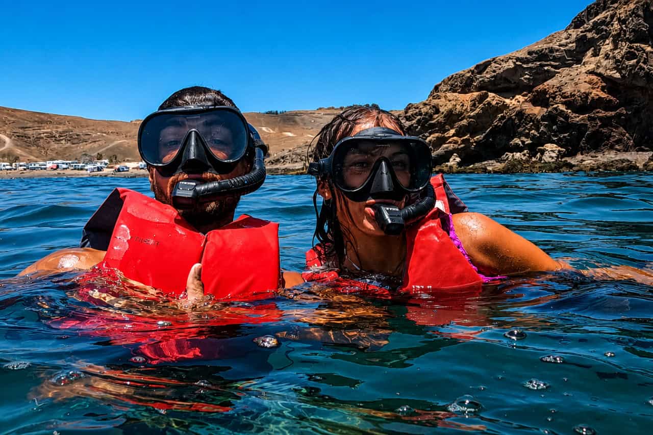 People diving into deep crystal-clear blue water during a snorkeling tour in Fuerteventura