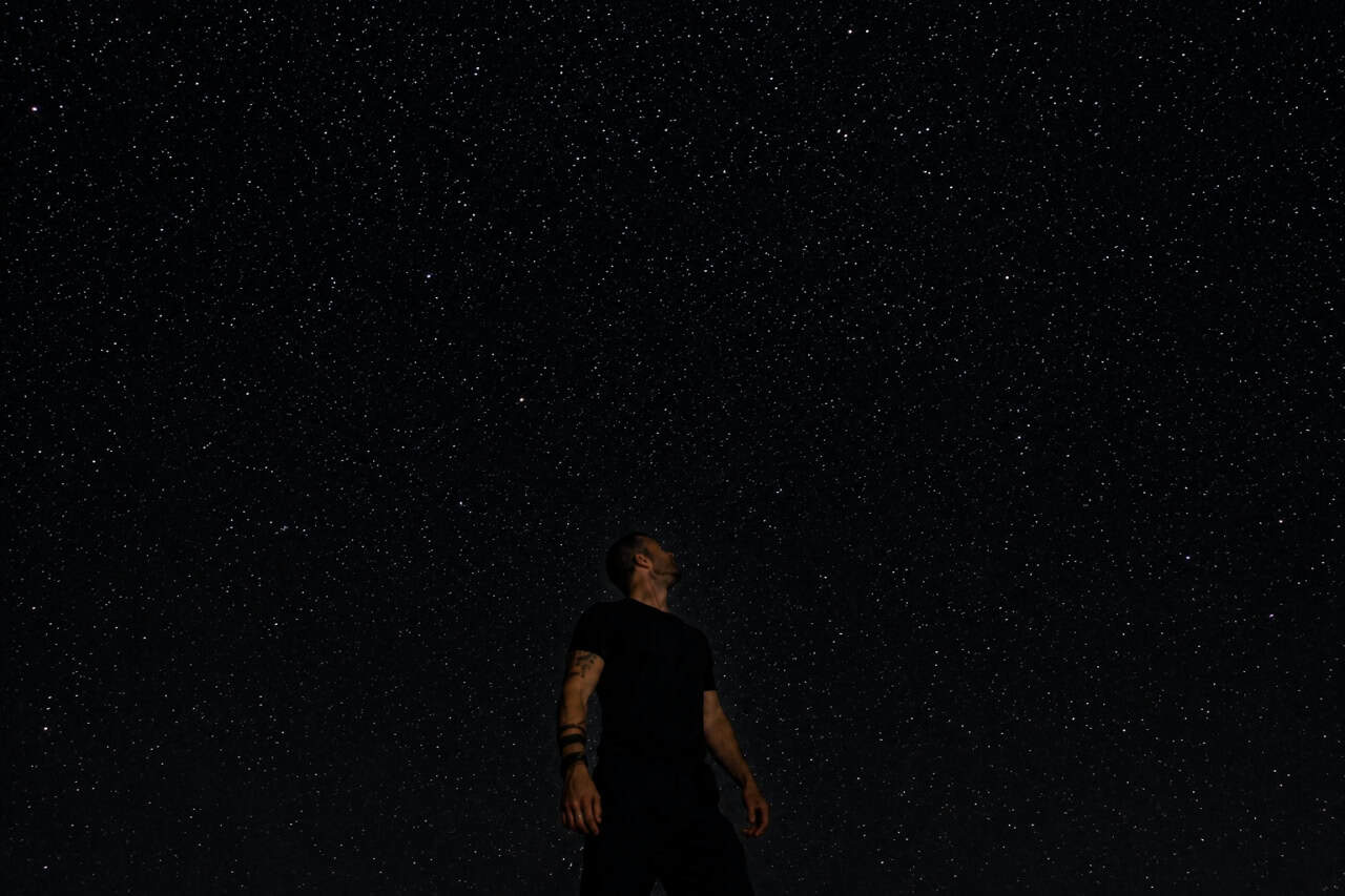 Person standing beneath a clear star-filled night sky during a stargazing experience in Gran Canaria, admiring the constellations in a peaceful mountain setting.