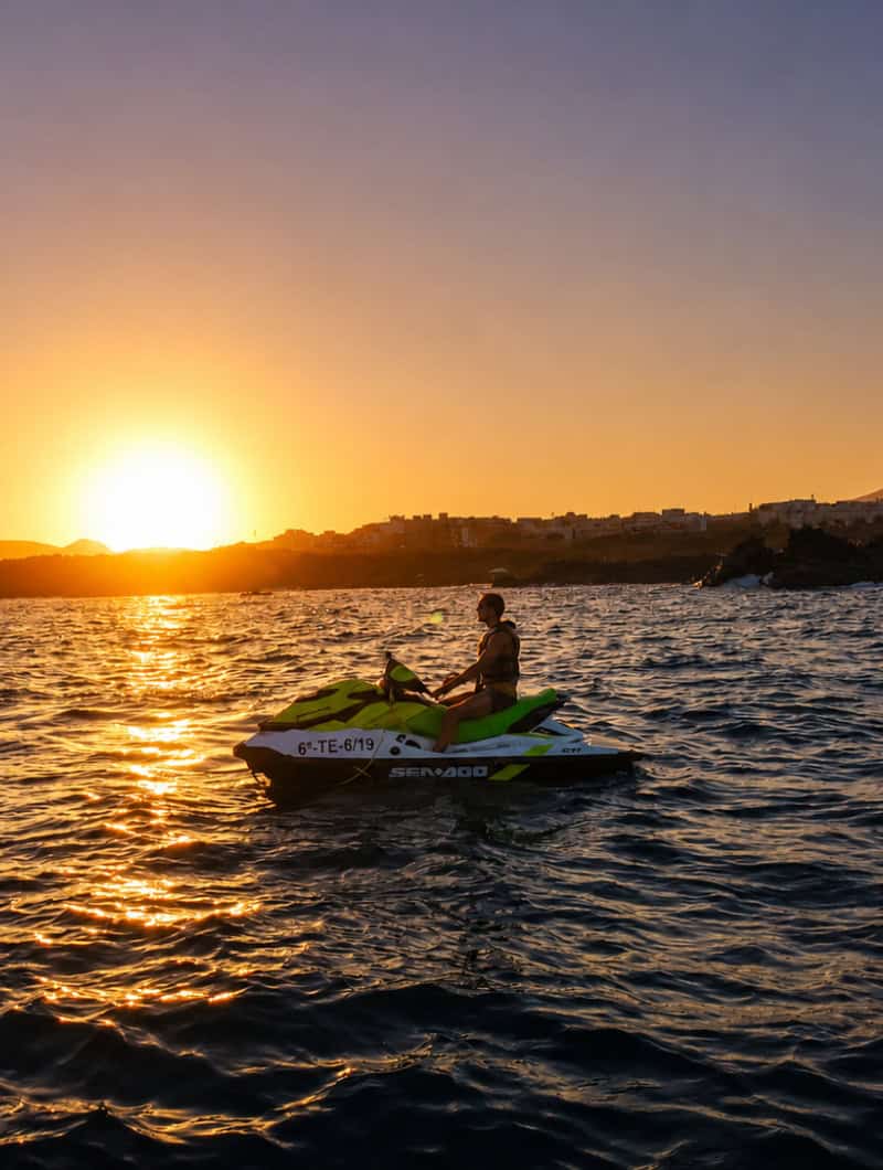 Rider on a Sea-Doo jet ski during a sunset jet ski rental experience in Tenerife with golden light across the ocean.