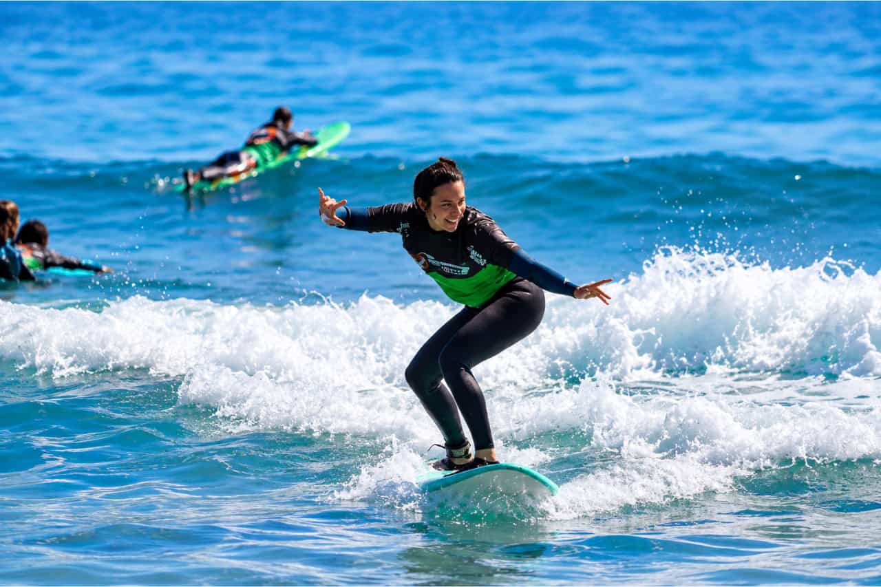 Surf student riding a wave during a beginner lesson in Corralejo, Fuerteventura