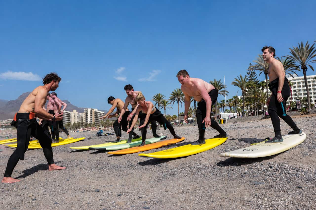 Surfboard floating on clear turquoise water with a breaking wave in the background, ideal for surfing in Tenerife's Atlantic Ocean.