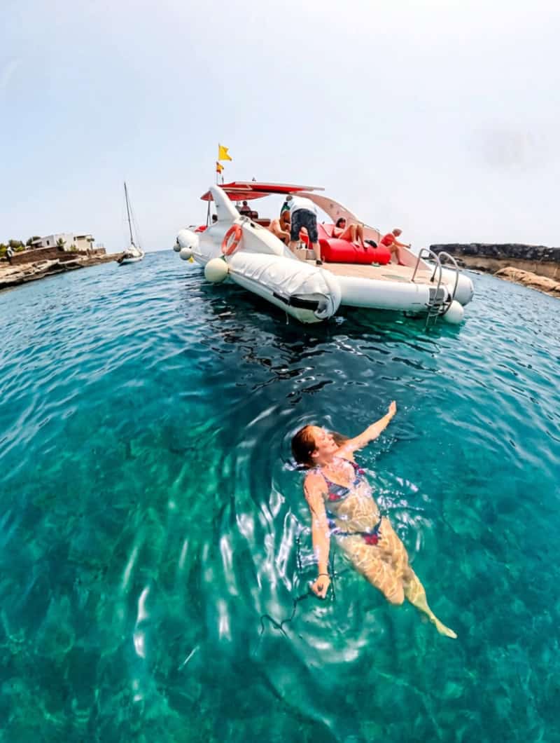 Guest swimming in clear water beside the Opera 60 during a private boat trip in Tenerife