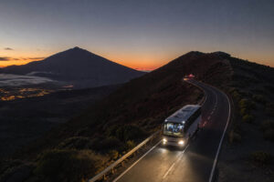 Tour bus driving through Teide National Park at night beneath the Milky Way, with volcanic landscapes and a star-filled sky creating the perfect setting for a Tenerife stargazing tour.